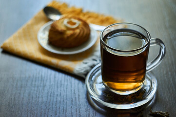 Green tea in glass cup with cookie on a white small plate on a dark wooden surface in summer
