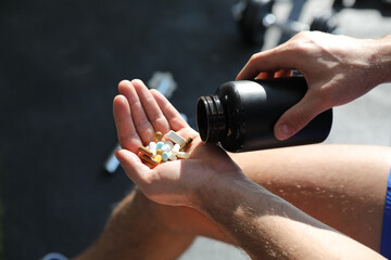 Sportsman with bottle of pills in gym, closeup. Doping concept