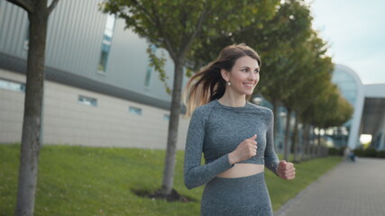 Young woman runner training in summer park city. Portrait of young and fit woman running and jogging alone on the empty street in city center wearing protective. Slow-motion shot