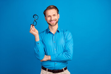 Photo of young cheerful man happy positive smile hold glasses wear shirt isolated over blue color background