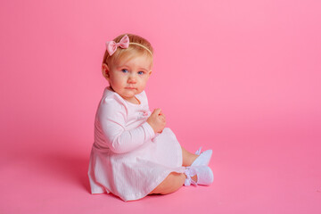 cute little baby girl in pink summer dress sitting on pink background