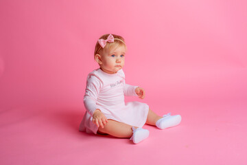 cute little baby girl in pink summer dress sitting on pink background