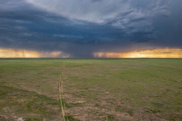 heavy storm cloud over green prairie and distant Rocky Mountains - Pawnee National Grassland in...