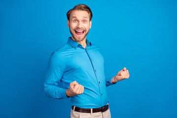 Profile side photo of young excited man happy positive smile celebrate victory lucky fists hands isolated over blue color background