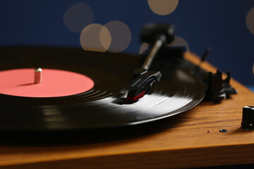 Obraz premium Vinyl record on turntable against blurred lights, closeup