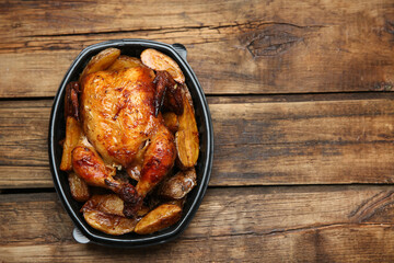 Top view of delicious grilled chicken with potato in plastic container on wooden table, space for text. Food delivery service
