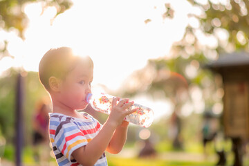 Adorable little happy boy drinking clean water. Child smile.  soft focus. Copy space.