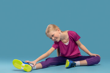 Girl sitting on floor bending over to outstretched leg