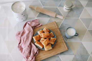 freshly baked homemade pastry on kitchen table. breakfast with puff buns and a glass of milk