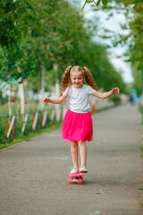 Naklejka premium little girl skateboarding in the park in summer