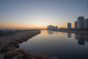 Fototapeta premium The silhouette of a building with the light of dawn and a river flowing through it 