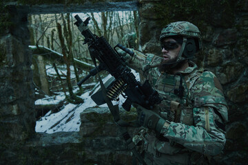 Portrait of airsoft player in professional equipment with machine gun in the forest. Soldier with weapons at war