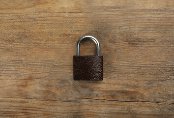 Modern padlock on wooden table, top view