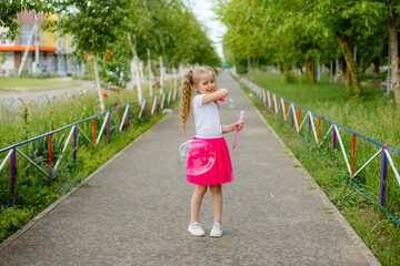 little girl blows soap bubbles in the Park in the summer