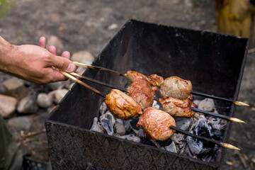 Person holding utensil and preparing meat on grill in back yard on a sunny day