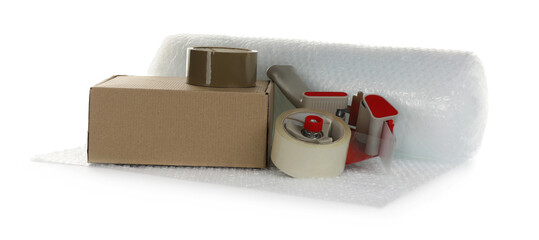 Bubble wrap roll, cardboard box and tape dispenser on white background