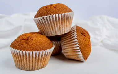 three cupcakes on a white background and white fabric close up