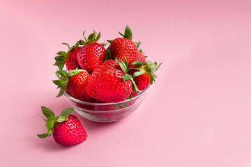 red strawberries in the plate on pink background