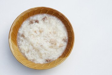Fototapeta na wymiar Top view of brown bowl of rice soup on white background. Concept easy menu for breakfast.
