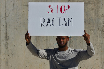 African american man raising a banner above his head against racism. Stop racism.
