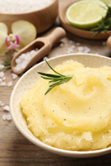 Body scrub with rosemary in bowl on wooden table, closeup