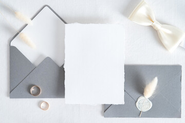 Wedding invitation card template. Flatlay blank paper card, grey envelopes, goled rings on white...