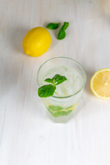 glass of cold lemon lemonade with mint and ice on white background
