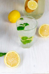 glass of cold lemon lemonade with mint and ice on white background