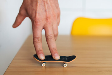Un homme joue avec sa planche à roulettes pour les doigts sur la table de son salon scandinave