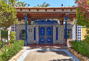 Pathway lined with green lush plants leading to the classic decorative ceramic azulejo tiled...
