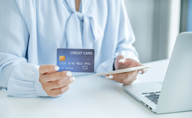Consumer woman hand holding a mock up credit card, ready to spending pay online finance shopping according to discount products via smart phone from home office