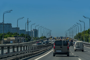 A toned image of a cityscape with sun flares. Car traffic on the road in summer in Moscow.