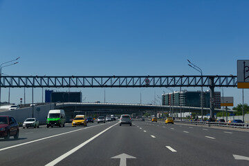 A toned image of a cityscape with sun flares. Car traffic on the road in summer in Moscow.