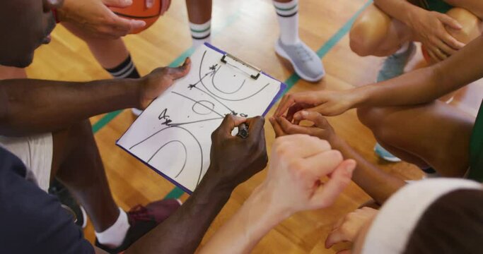 Diverse female basketball team and coach discussing game tactics