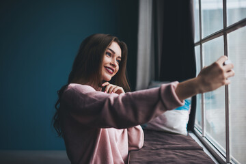 Happy woman taking selfie near window