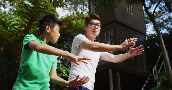 Happy asian fother exercising in garden with sonr, practicing tai chi together