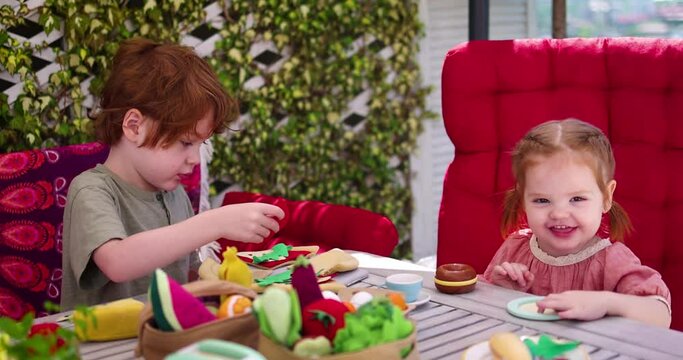 happy kids playing with felt food toys, setting a table for dinner, role play games at summer day in a garden