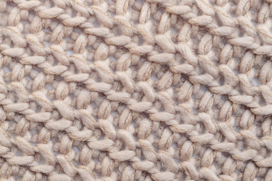Close up of beige textile texture. Woolen knitted fabric background. Detailed warm woolen scraf.