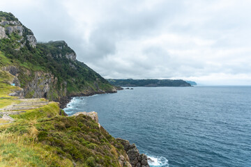Fototapeta na wymiar Cliffs next to the Santa Catalina de Lekeitio lighthouse on a cloudy spring morning, with the sea in the background, landscapes of Bizkaia. Basque Country