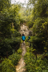 Two hikers in raincoats walking through a forest in the rain. Spring on the road from Ispaster to Lekeitio, landscapes of Bizkaia. Basque Country