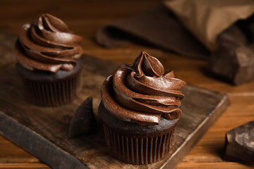 Delicious chocolate cupcakes with cream on wooden table