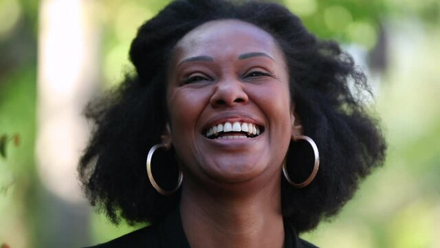Black woman laughing and smiling outside, happy joyful African person