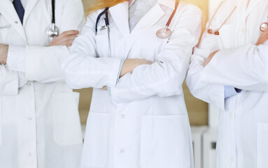 Group of modern doctors standing as a team with arms crossed in hospital office, close-up. Medical help, insurance in health care, best treatment and medicine concept