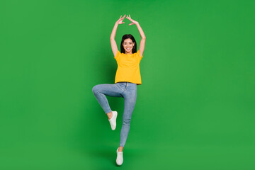 Full length photo of cheerful active young woman jump up air ballet dance isolated on green color background