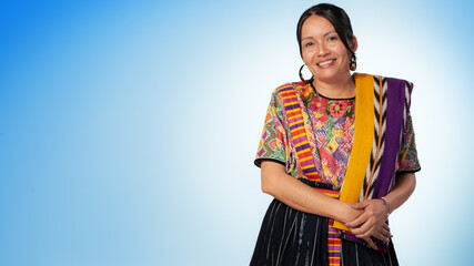 Smiling indigenous woman looking at the camera, wearing a colorful dress.