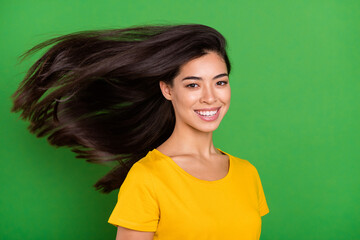 Fototapeta premium Photo portrait of girl with long brunette hair flying on wind smiling overjoyed isolated on bright green color background copyspace