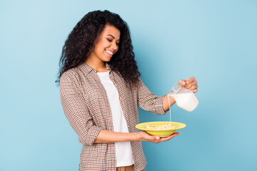 Photo of charming pretty dark skin woman dressed checkered shirt cooking milk cereal isolated blue...