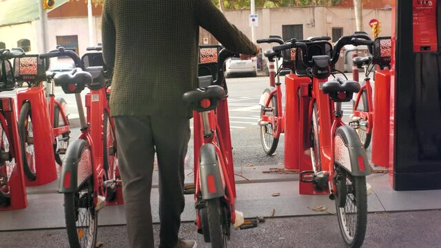 Tourist man take Electric Kick scooter or bike bicycle in sharing parking lot, tourist phone application. New sharing business project started in city, eco transportation