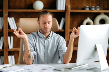 Relaxed peaceful young adult caucasian manager, businessman or office employee, sitting in office...
