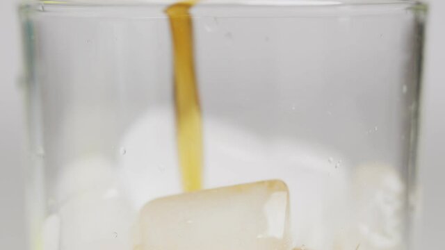 Slow motion 4K. A sweet  cold soft drink is poured into a glass filled with ice cubes. refreshing delicious drink Thirst quenching drink.
